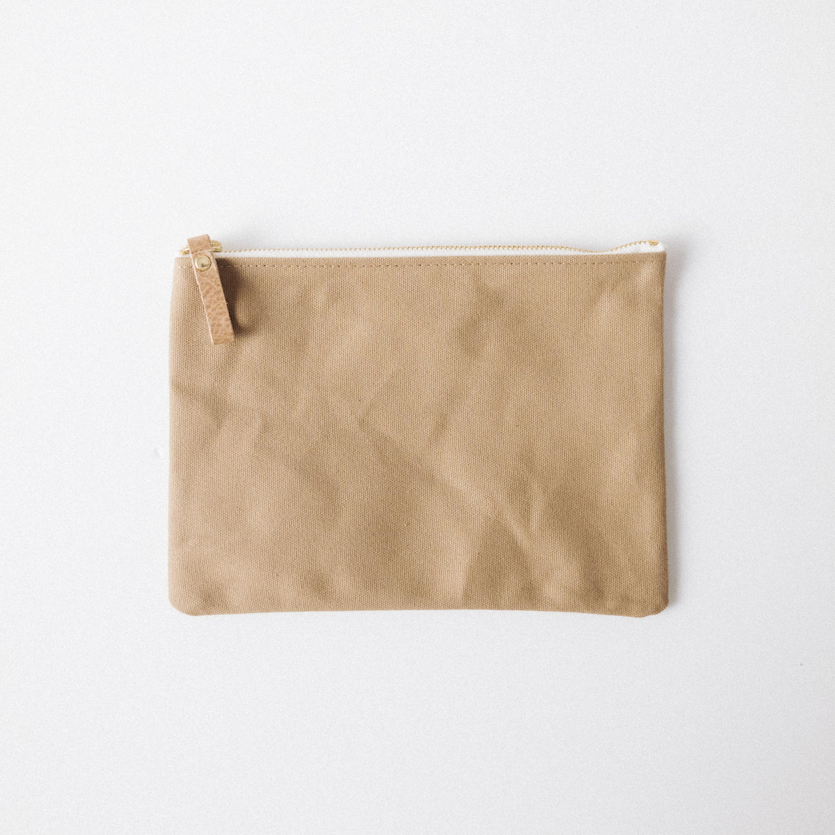 Handmade tan cotton canvas zip pouch with a solid brass zipper and durable leather pull for easy organization.
