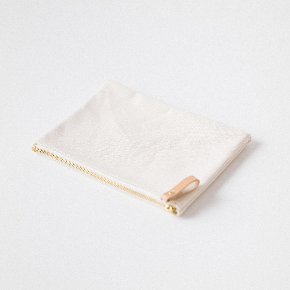 Handmade heavyweight cotton canvas zip pouch with a solid brass zipper and leather pull for effortless organization.