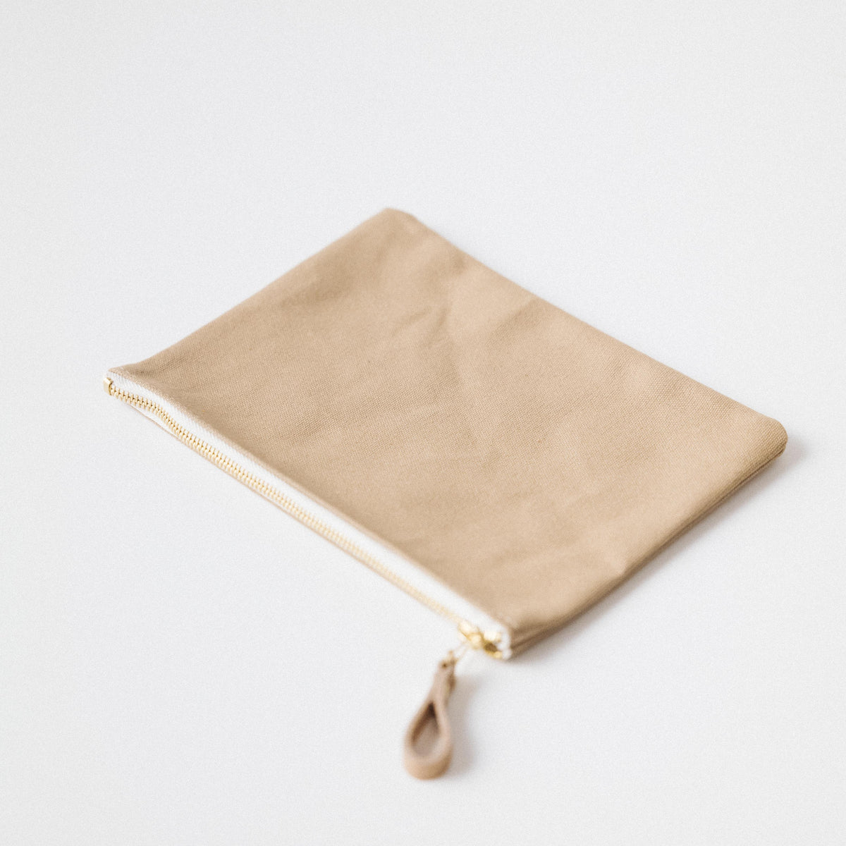Handmade tan cotton canvas zip pouch featuring a durable solid brass zipper and a convenient leather pull tab.