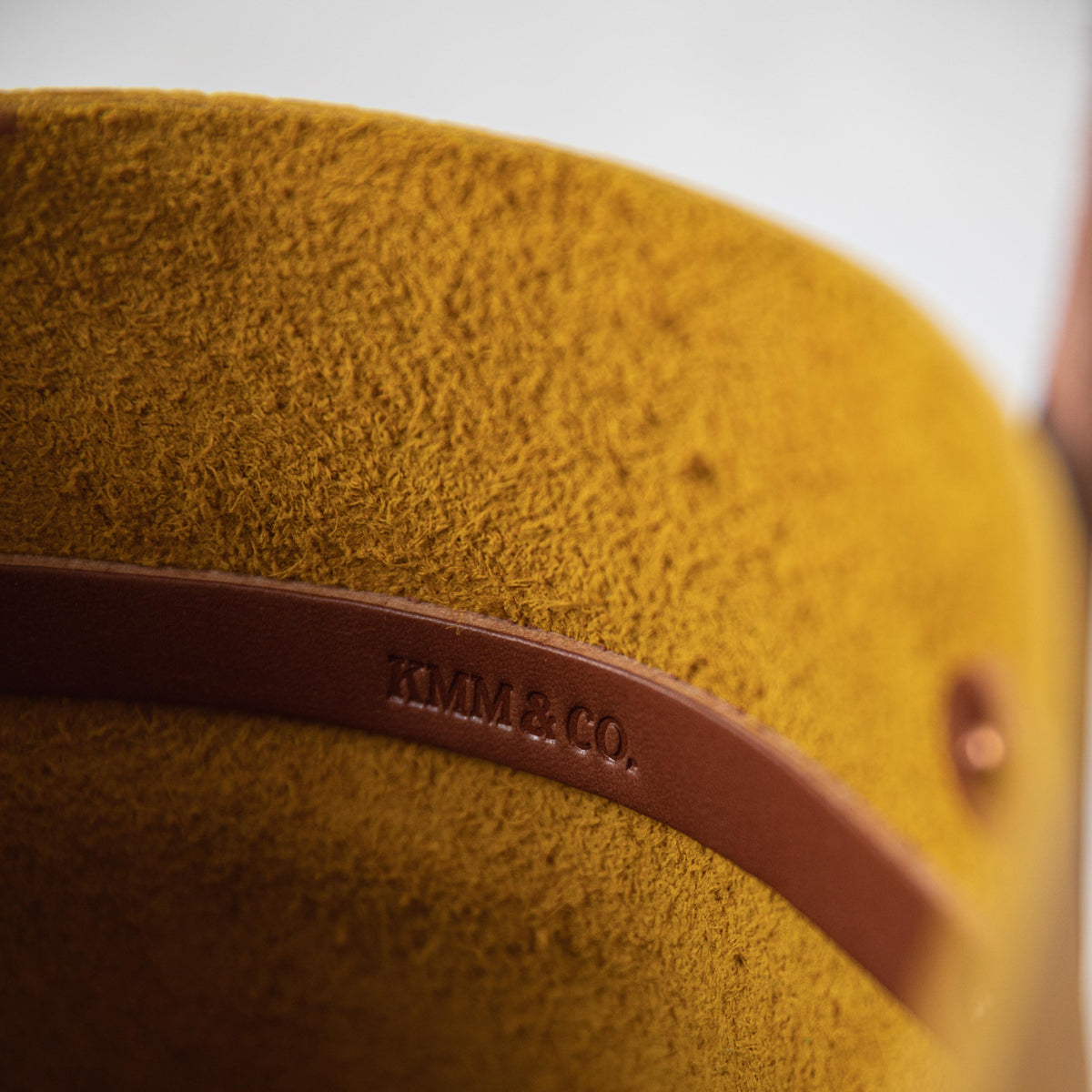Close-up of the Yellow Bison Tote, showcasing its vibrant yellow leather with a prominent grain and soft temper. Tan leather strap with "KMM & CO." embossed.