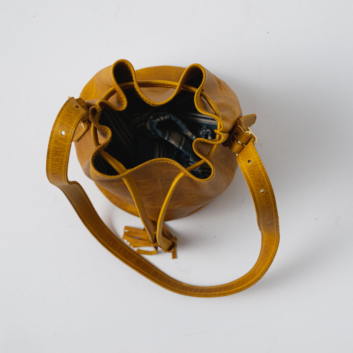 Vibrant Yellow Bison full-grain leather bucket bag with a soft temper, prominent grain, and adjustable strap.