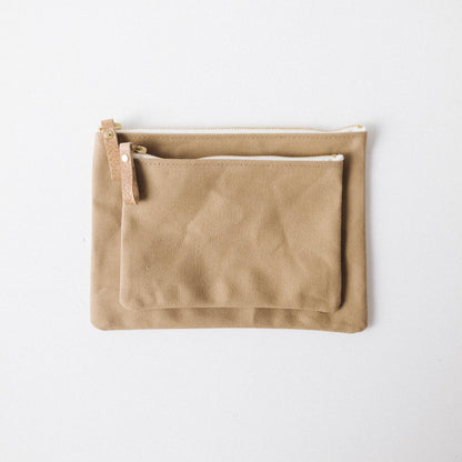 Two handmade tan cotton canvas zip pouches with solid brass zippers and leather pulls, perfect for organizing your tote.