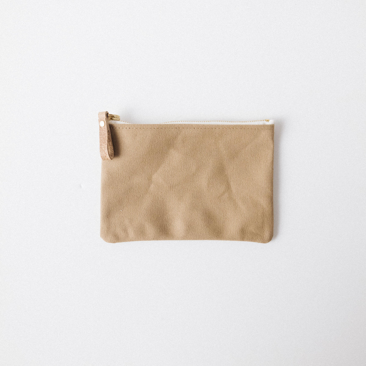 Handmade tan cotton canvas zip pouch with a solid brass zipper and durable leather pull for easy organization.