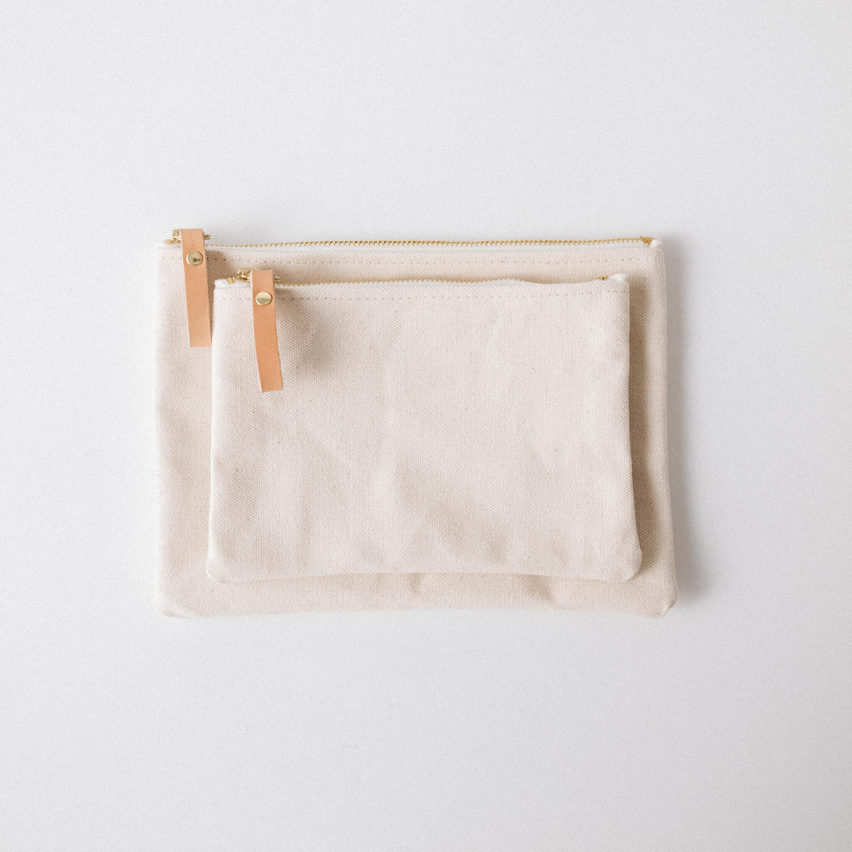 Handmade heavyweight cotton canvas zip pouches in small and medium sizes with solid brass zippers and leather pulls.
