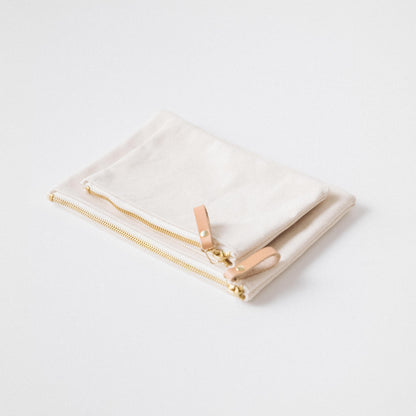 Two handmade heavyweight cotton canvas zip pouches with solid brass zippers and elegant leather pulls.
