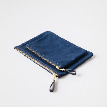 Two navy blue heavyweight cotton canvas zip pouches with solid brass zippers and leather pulls.