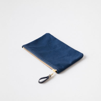 Navy blue heavyweight cotton canvas zip pouch with a solid brass zipper and matching leather pull.