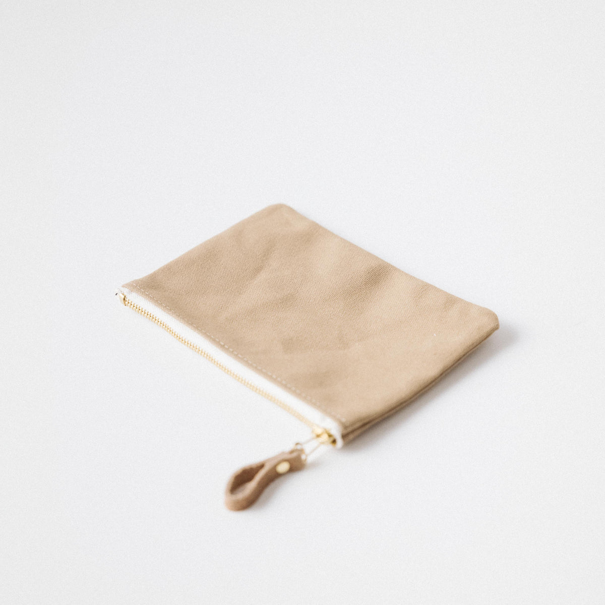 Handmade tan heavyweight cotton canvas zip pouch with a solid brass zipper and stylish leather pull.