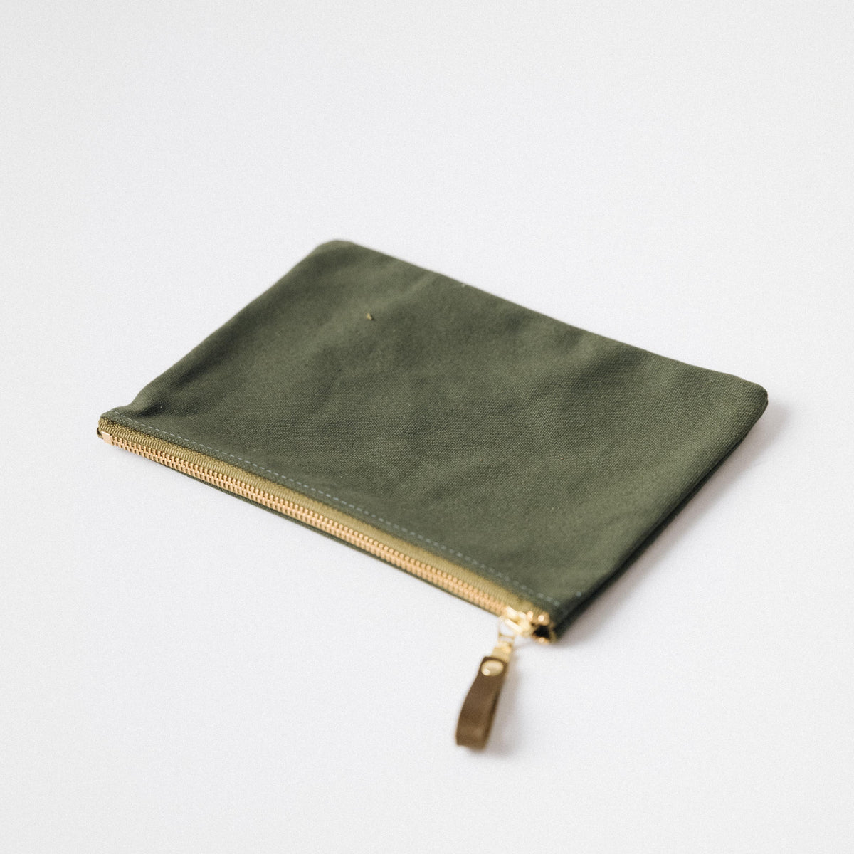 Olive green heavyweight canvas zip pouch with a solid brass zipper and leather pull for easy organization.