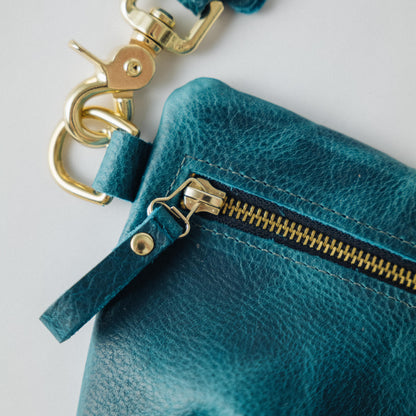 Petrol blue bison leather belt bag featuring a solid brass zipper, matching leather pull, and adjustable chain link strap.