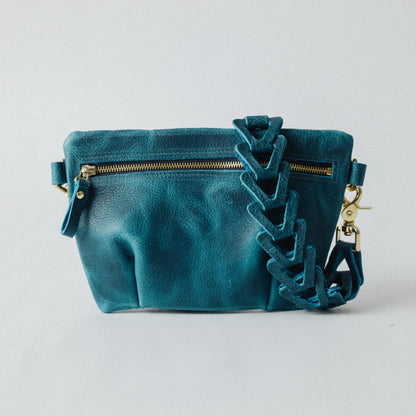 Petrol blue bison leather belt bag with a pleated design, brass zipper, and adjustable leather chain link strap.