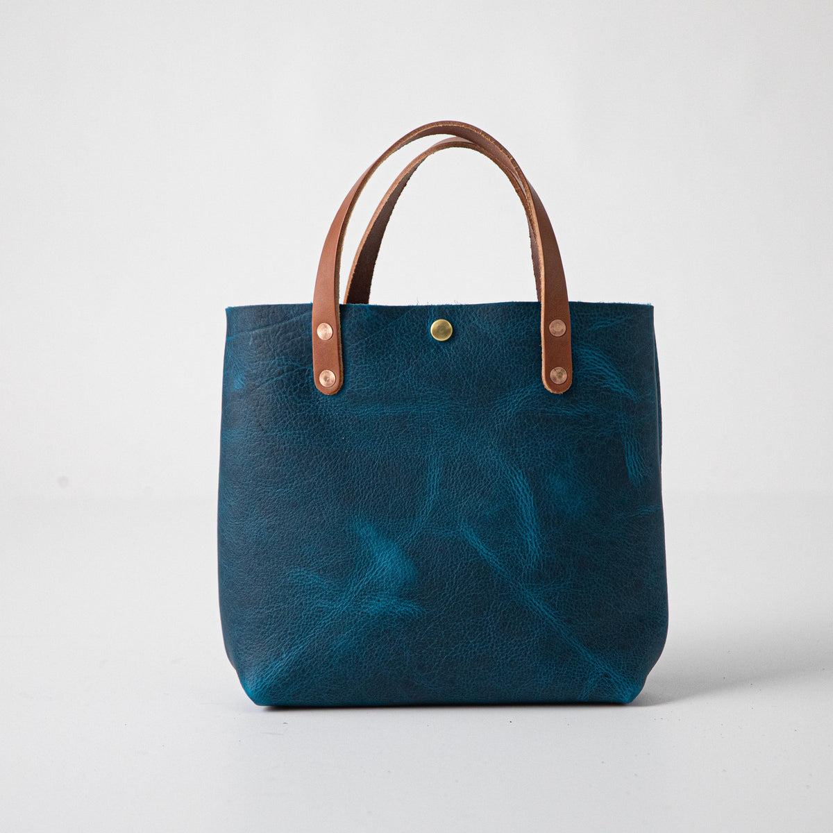 Petrol Blue Bison Mini Tote: vibrant blue full-grain leather, tan handles, and a single brass snap closure.