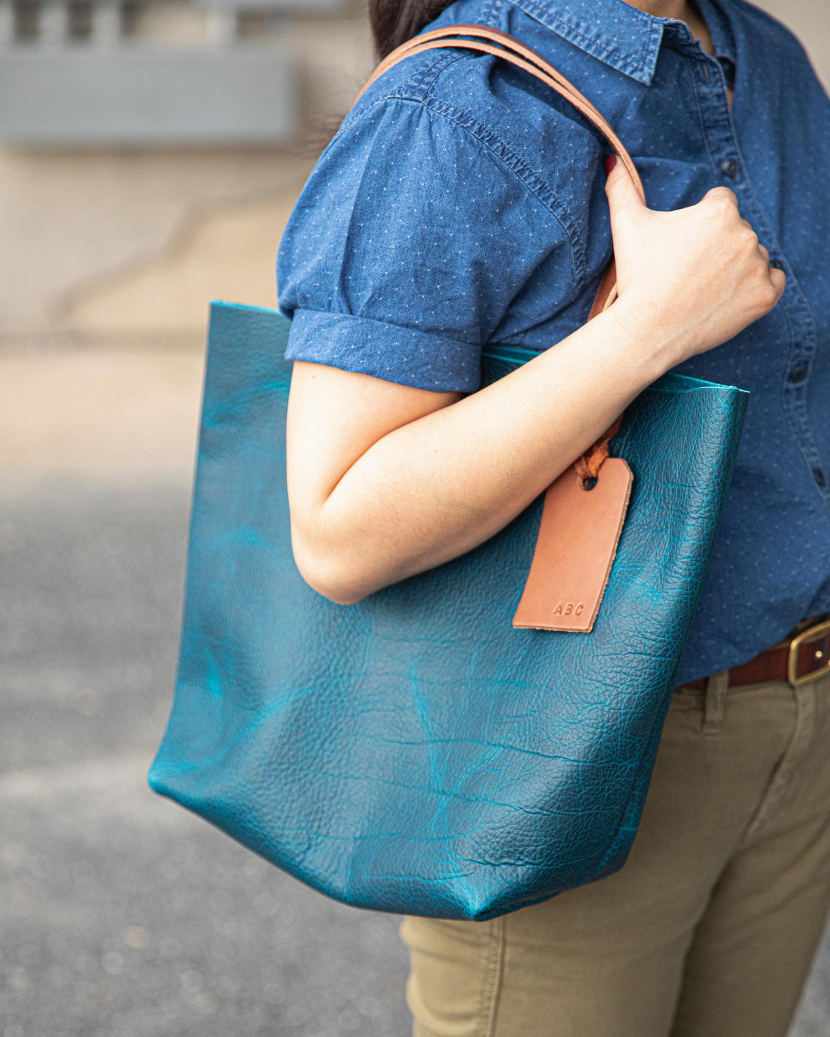 Handmade Petrol Blue Bison leather tote bag with natural grain and tan leather handles, worn over the shoulder.