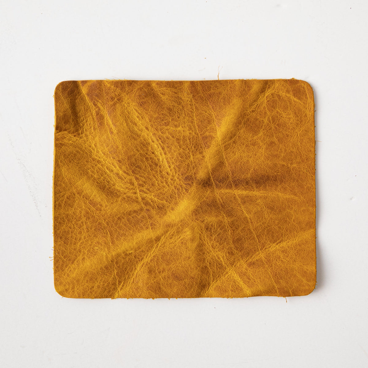 Close-up of a square Yellow Bison leather swatch, showcasing its vibrant yellow hue, prominent grain, and soft temper.