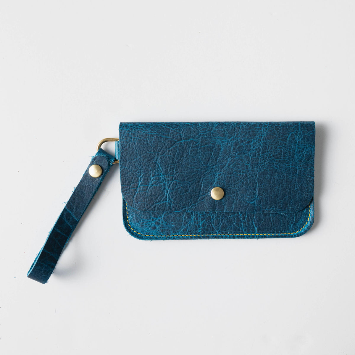 Petrol Blue Bison Wristlet Clutch: full-grain leather, 8.5x5.25 inches, with a 5.5-inch strap and brass snap.