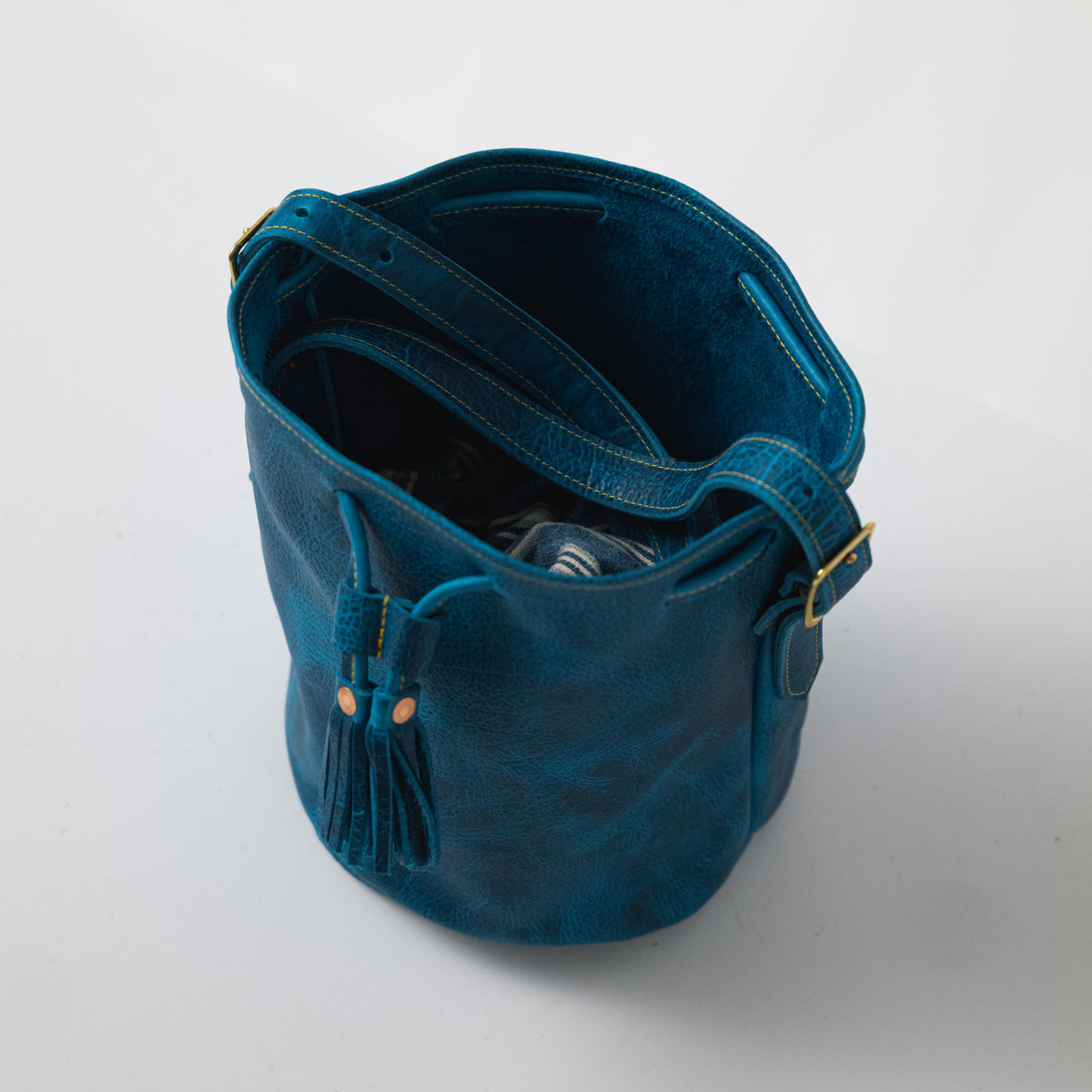 Petrol Blue Bison Bucket Bag: chic, pebbled leather with drawstring closure, playful tassels, and comfortable strap.