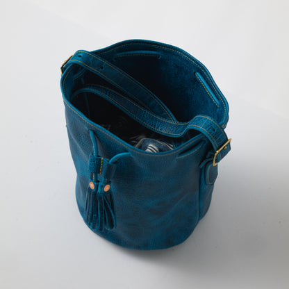 Petrol Blue Bison Bucket Bag: chic, pebbled leather with drawstring closure, playful tassels, and comfortable strap.