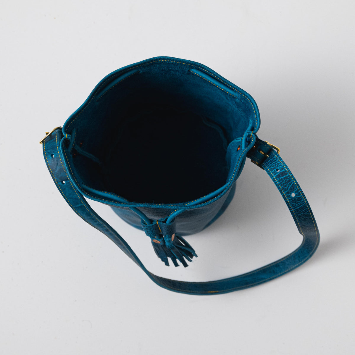 Petrol Blue Bison Bucket Bag: classic leather silhouette with drawstring closure, playful tassels, and comfortable shoulder strap.