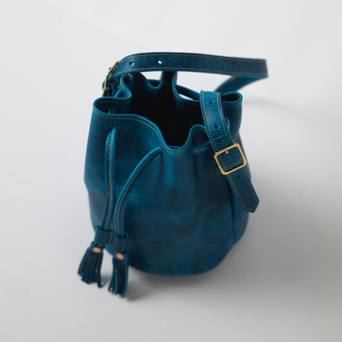 Petrol Blue Bison Bucket Bag: chic leather drawstring bag with playful tassels and adjustable strap.