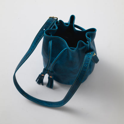 Petrol blue bison leather bucket bag with drawstring closure, elegant tassels, and a comfortable shoulder strap.