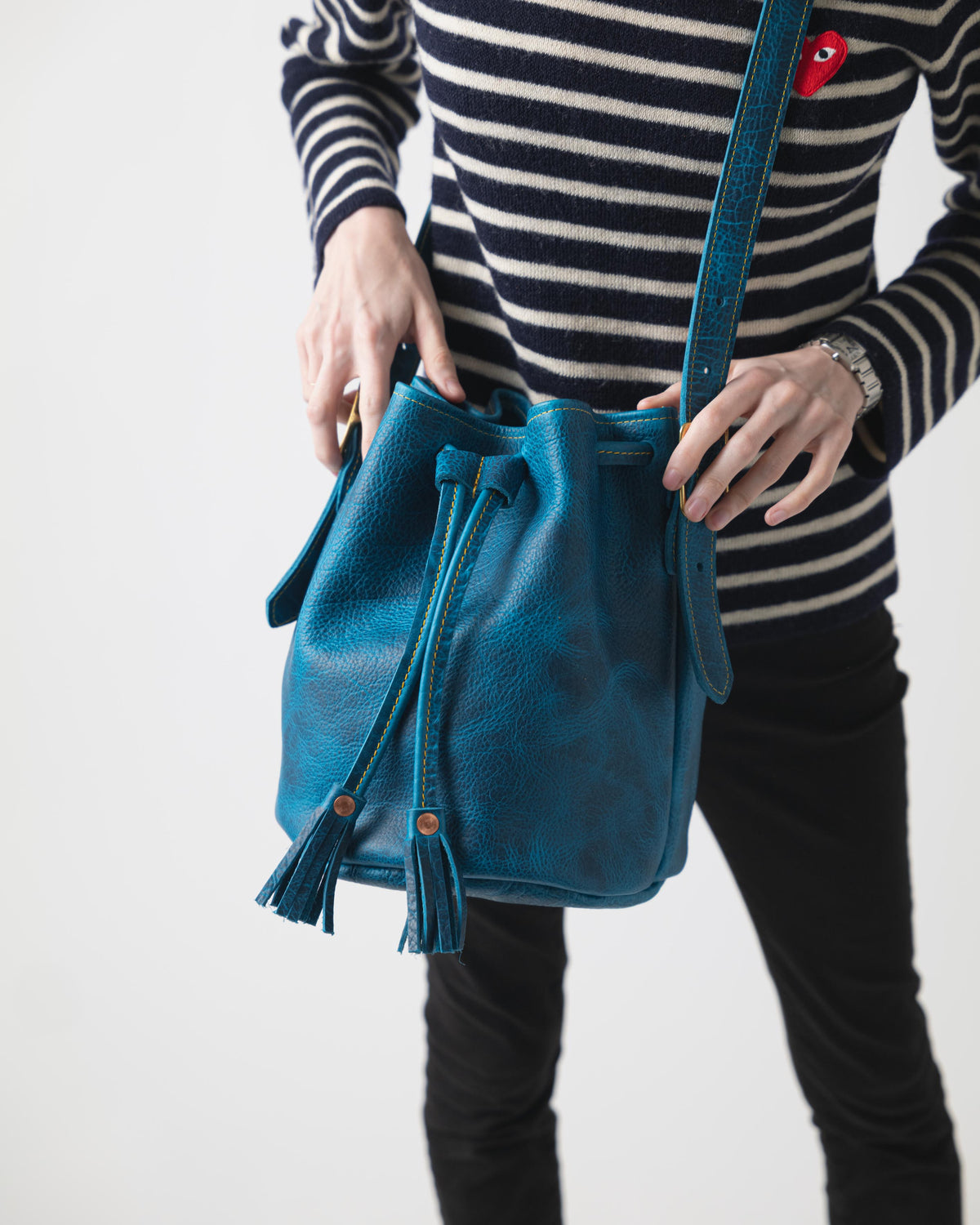 Petrol Blue Bison Bucket Bag: luxurious leather with playful tassels, drawstring closure, and comfortable strap.