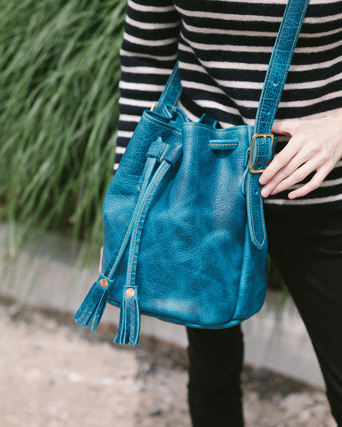 Petrol Blue Bison Bucket Bag with drawstring closure, playful leather tassels, and adjustable strap.